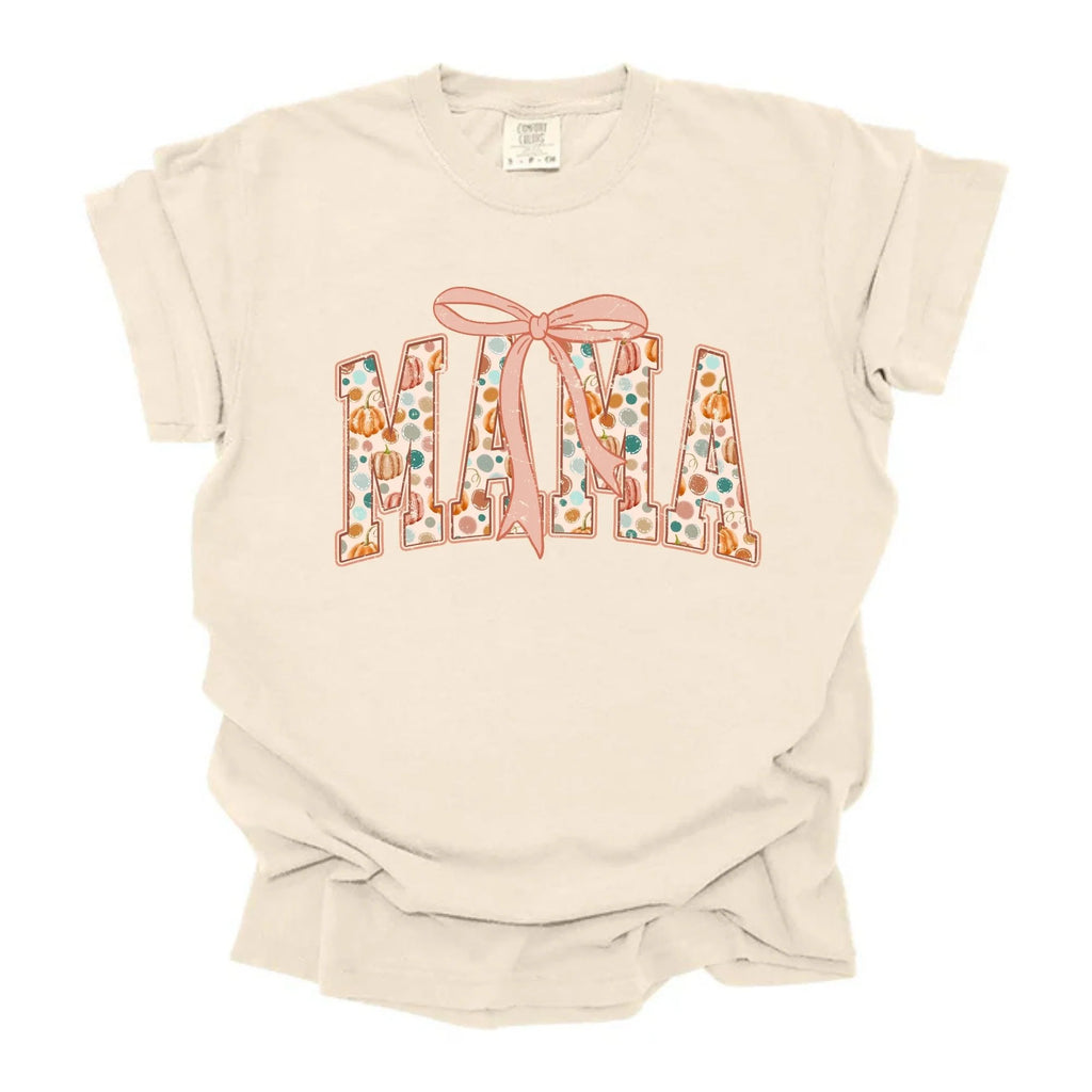 Ivory Comfort Colors tee with MAMA spelled out in polka dot pumpkin patterned letters topped with a pink coquette bow
