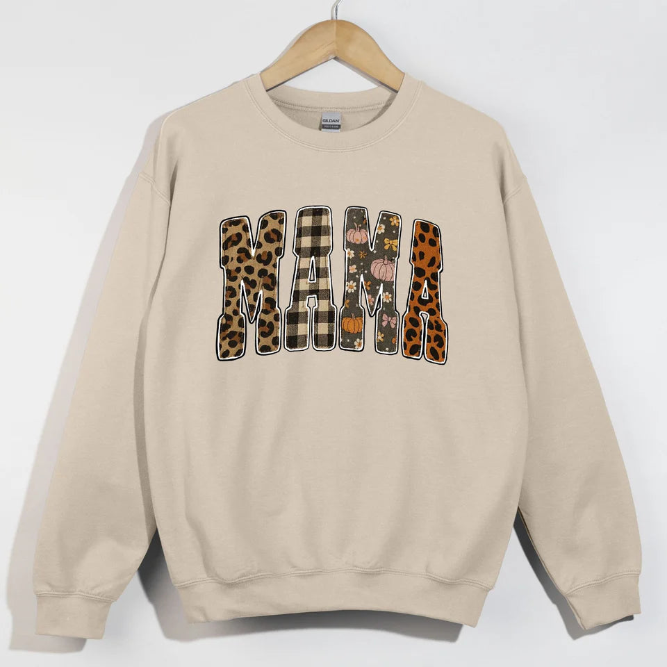Sand crewneck sweatshirt with MAMA spelled out in fall-themed patterned letters including leopard print, buffalo plaid, and pumpkin floral designs