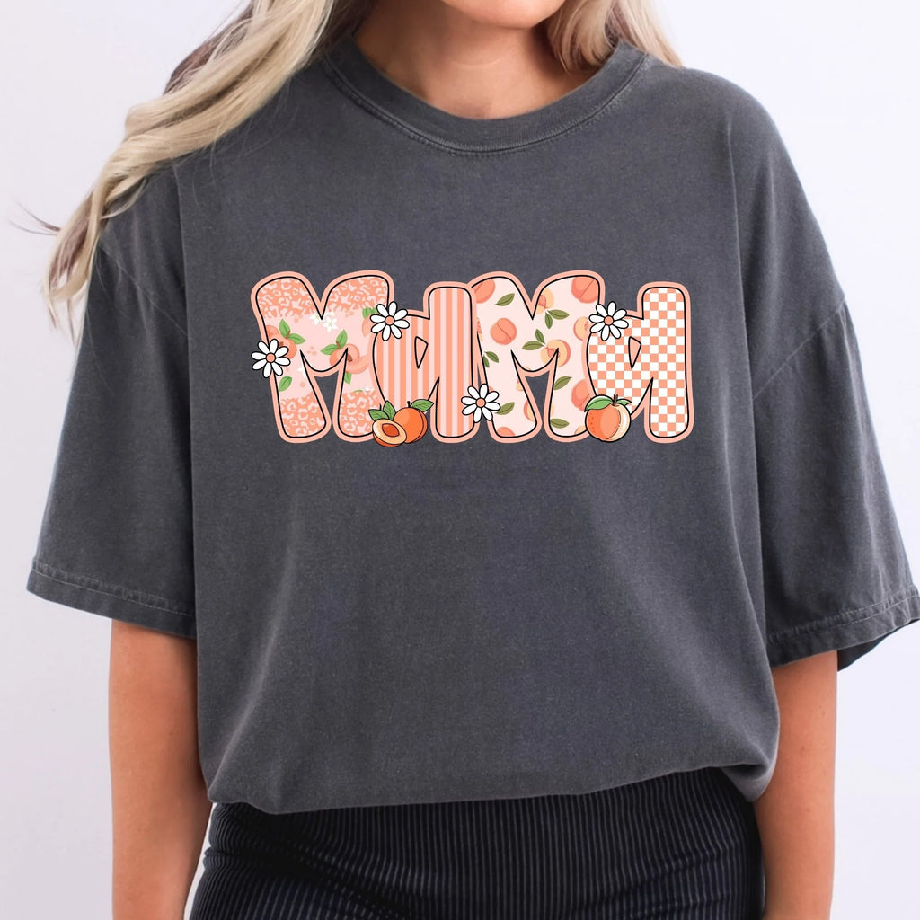 Charcoal Comfort Colors oversized tee with MAMA in peachy patterned bubble letters featuring leopard stripes peach floral and checkerboard fills with daisy and peach accents