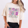 Ivory Comfort Colors oversized tee with colorful Motherhood graphic in checkered floral and glitter patterned letters with quote some days I rock it some days it rocks me either way we're rockin'