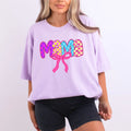 Lavender Comfort Colors oversized tee with mama in vibrant checkered bubble letters in pink, purple, yellow, and blue with hot pink coquette bow