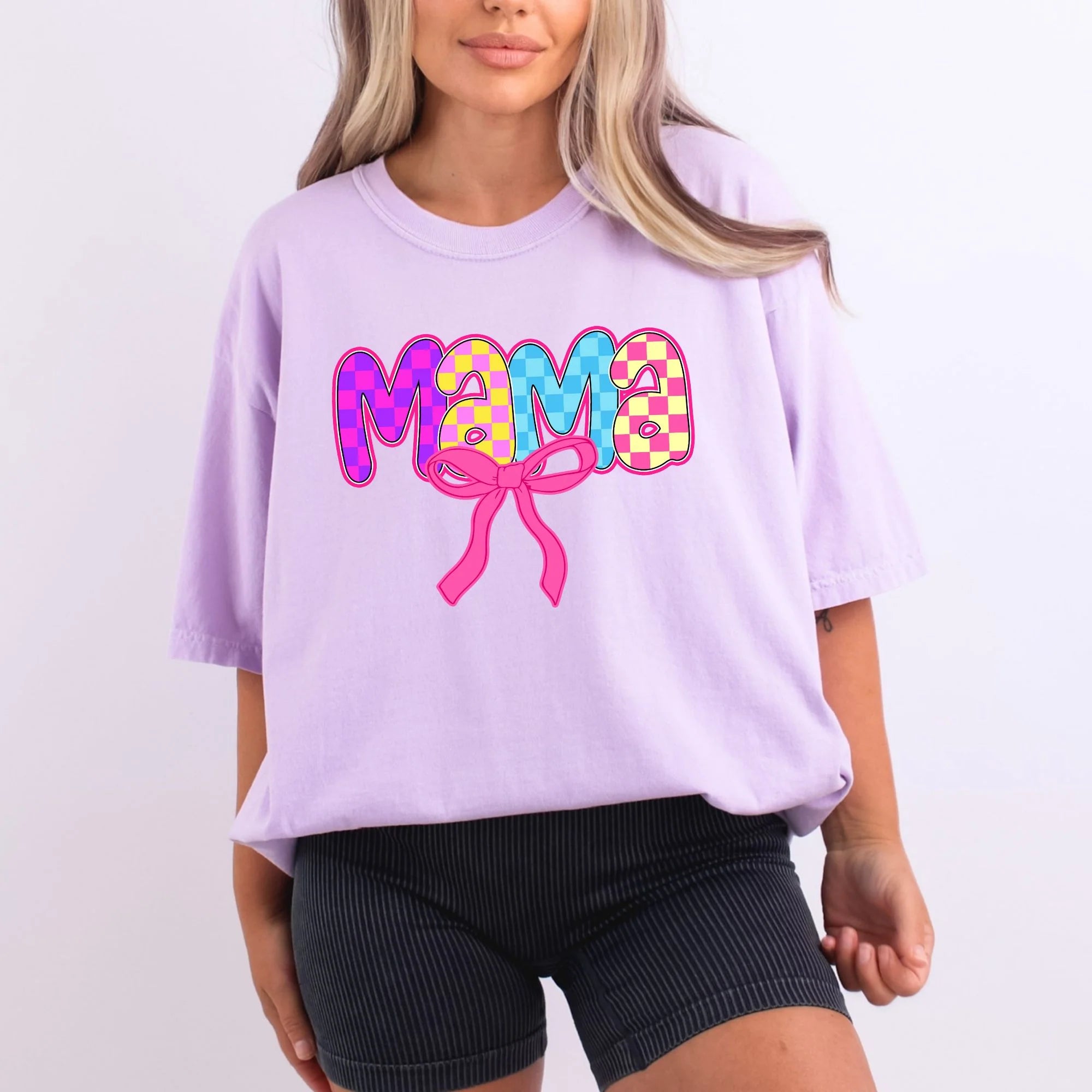 Lavender Comfort Colors oversized tee with mama in vibrant checkered bubble letters in pink, purple, yellow, and blue with hot pink coquette bow