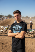Person wearing Weekend Warrior Moto Club black tee at outdoor motocross event
