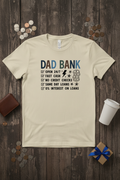 Dad Bank T-Shirt styled with wallet, coins, and coffee cup on rustic wood