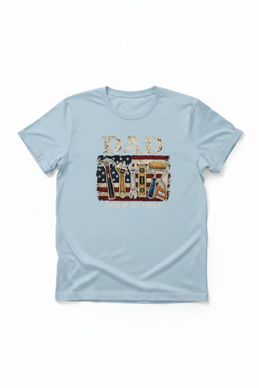 Dad Fixer of All Things T-Shirt flat lay on white background showing patriotic tools graphic