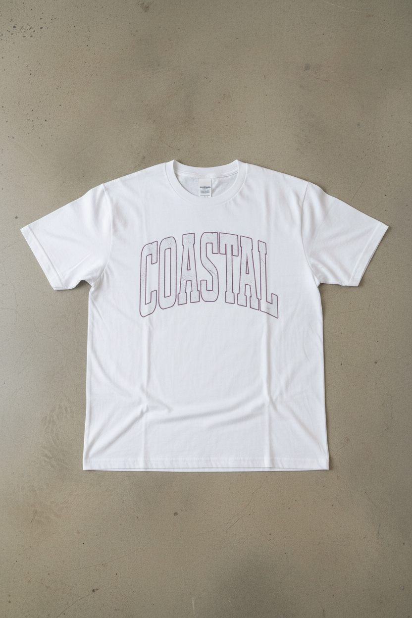 Coastal vintage collegiate graphic on white t-shirt flat lay