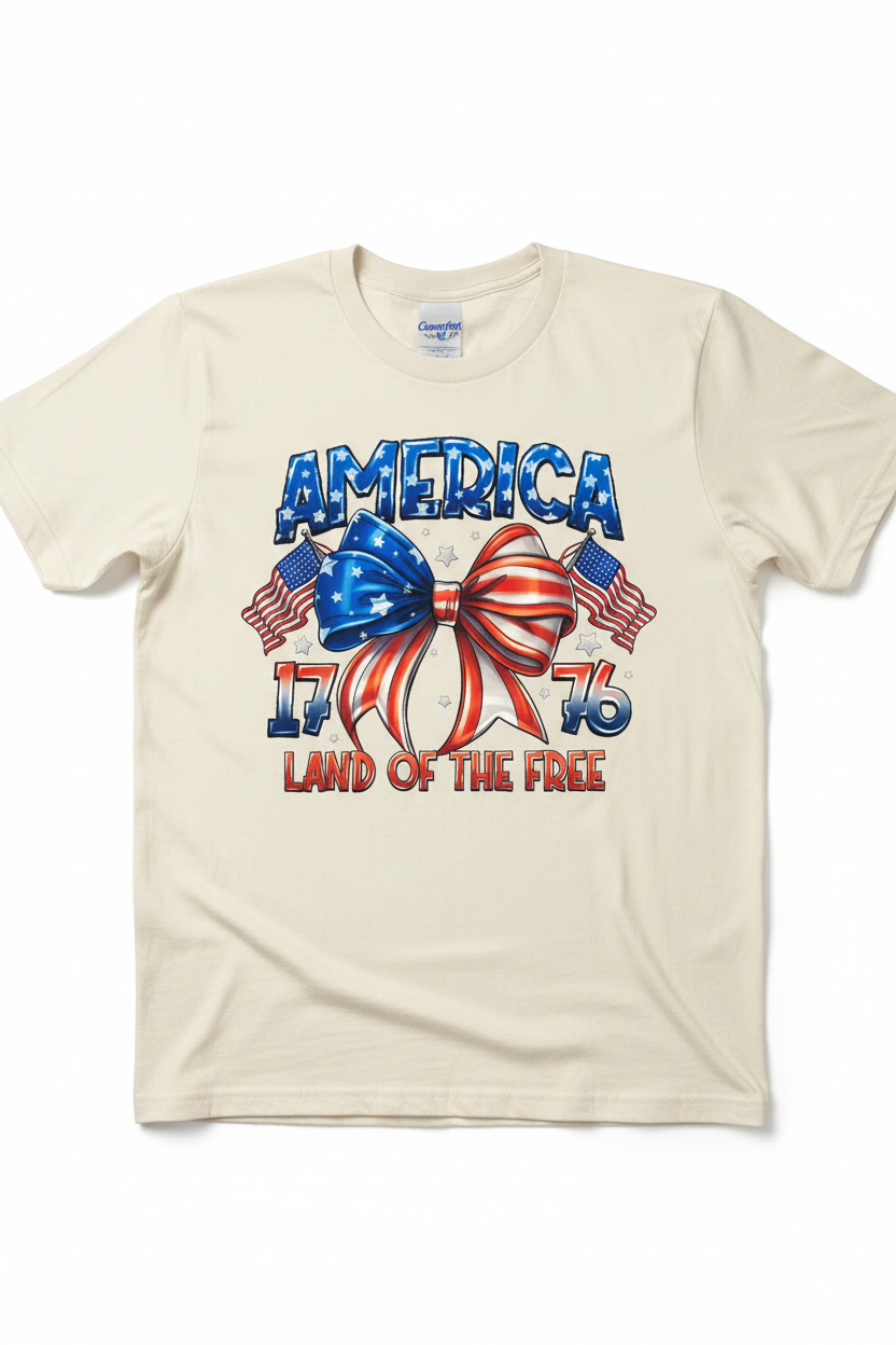 America 1776 Land of the Free T-Shirt flat lay on natural ivory tee showing patriotic bow graphic