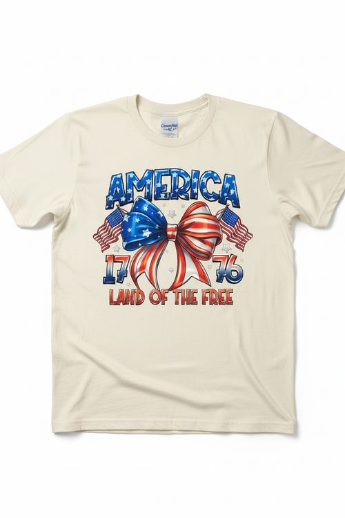 America 1776 Land of the Free T-Shirt flat lay on natural ivory tee showing patriotic bow graphic